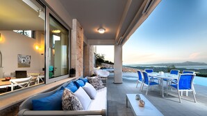 Ein moderner Außenbereich zum Leben mit einer Couch, einem Esstisch und Stühlen, mit Blick auf eine reizvolle Landschaft.