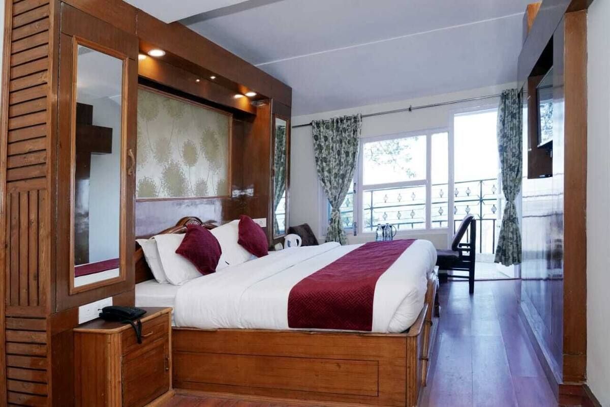 Un dormitorio con una cama de madera, una mesita de noche, un espejo grande y vistas al balcón.