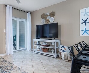 A living room with a TV on a stand, a dining table, and a sliding glass door.