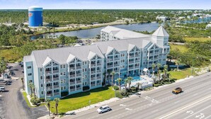 A multi-story hotel with a pool, located near a body of water and a road. - Charming 1BR/1B~sleeps 6~Gym, Pool, & Boat Parking (Orange Beach)