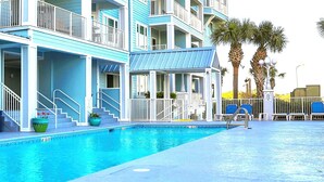 A hotel with a pool, balconies, and palm trees. - Charming 1BR/1B~sleeps 6~Gym, Pool, & Boat Parking (Orange Beach)