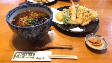 A bowl of ramen with noodles, broth, and toppings, a plate with tempura, and a small dish of pickled ginger.