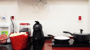 Et køkken med en rødbedefarvet bordplade, en kaffemaskine, en stegepande og en popcornbeholder.