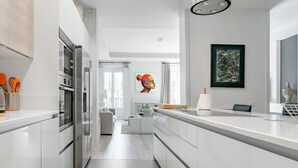 Una cocina moderna con armarios blancos, electrodomésticos de acero inoxidable y una isla central.