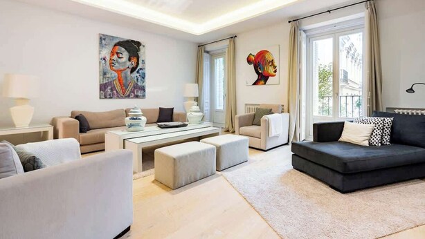 Una sala de estar moderna con un sofá, sillones, una mesa de centro y obras de arte en las paredes.