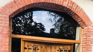 A wooden double door with a brick archway, featuring two circular windows and a metal handle. - La Maison Gavraise - Stunning house (and Attached Barn) in the Centre of Gavray. (Gavray-sur-Sienne)
