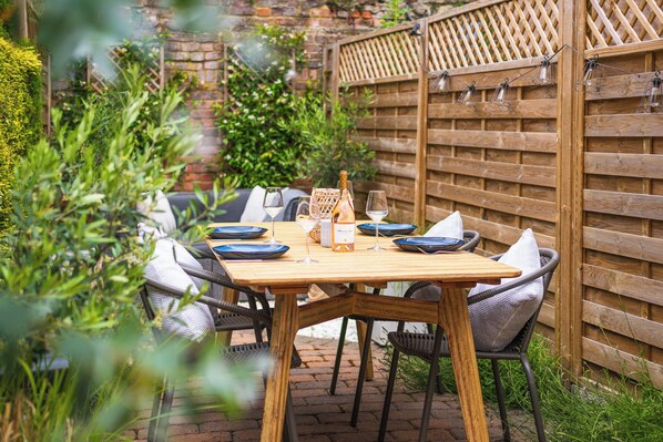 A wooden table set for two with a bottle of champagne, glasses, and a menu.