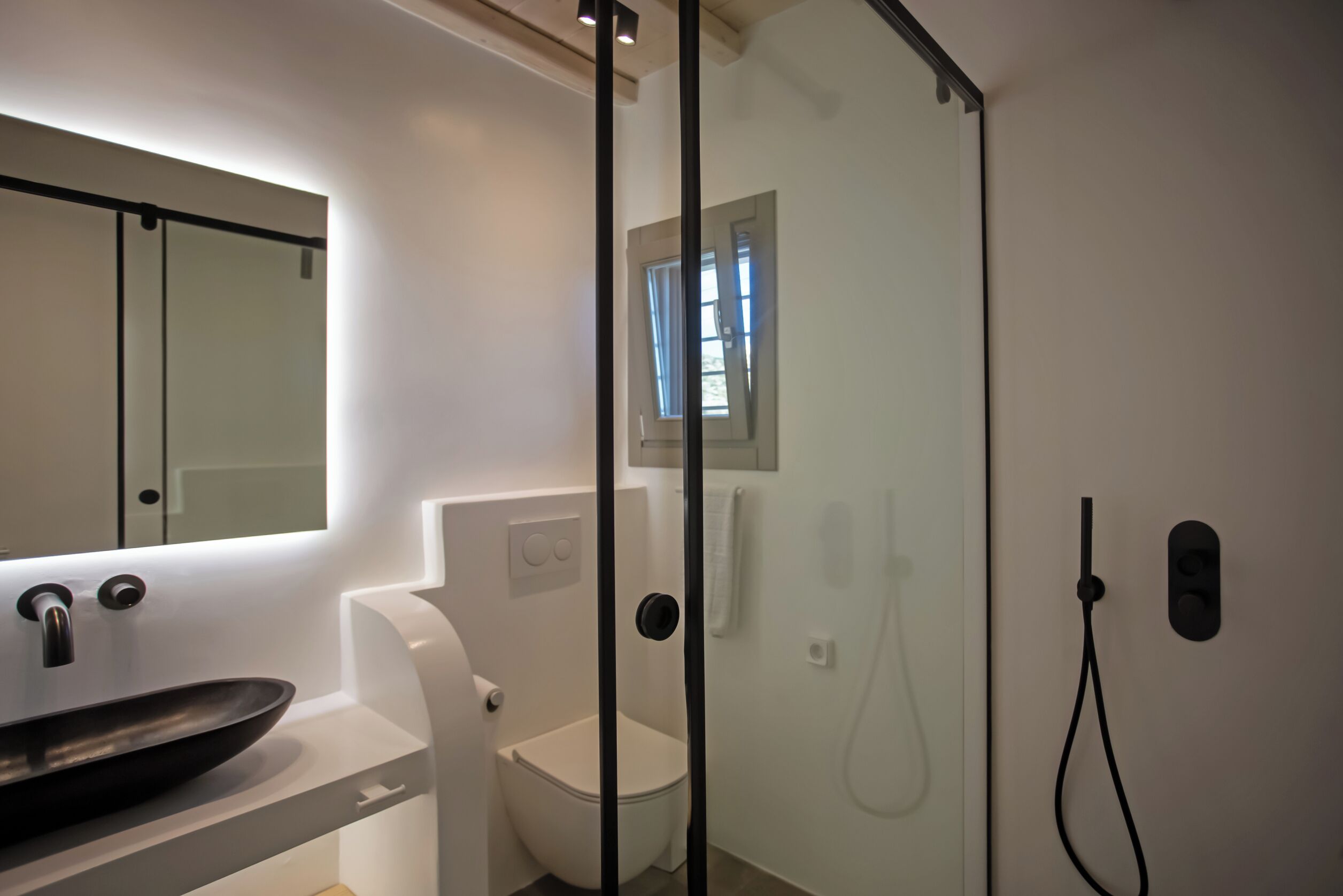 A modern bathroom with a glass-enclosed shower, a white sink, and a toilet.