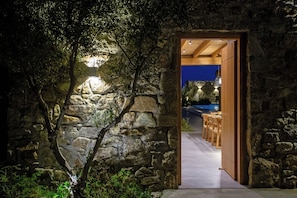 A stone-walled corridor leading to a wooden interior with a bar area.