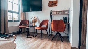 A modern living room with a flat-screen TV, two leather chairs, a coffee table, and a wooden sign on the wall.