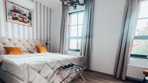 Una camera da letto con un letto, un lampadario, una finestra con tende e un quadro appeso al muro.