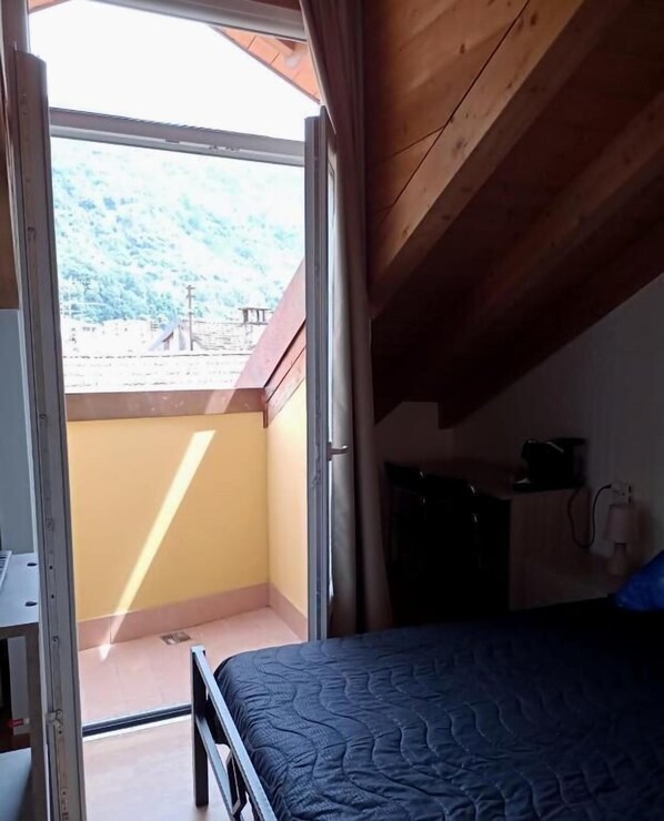 A bedroom with a bed, a desk, and a view of a balcony. - L'Angelo (Omegna)