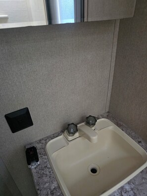 Bathroom features a single sink with two faucets and a small electrical outlet.