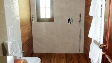 Een moderne badkamer met een houten vloer, een inbouw raam, een douche en een toilet.