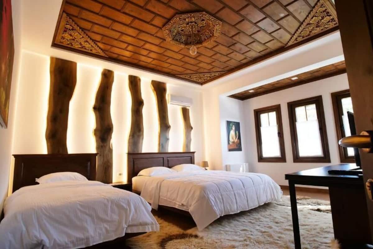 A bedroom with two beds, wooden headboards, a large mirror, and a ceiling with a geometric pattern.