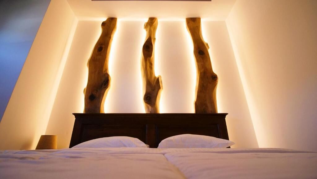 A bedroom with a wooden headboard, a bedside table, and a lamp.