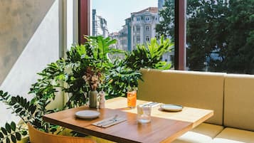 A dining table with plates, cutlery, and a glass of iced tea, set against a window with a city view.