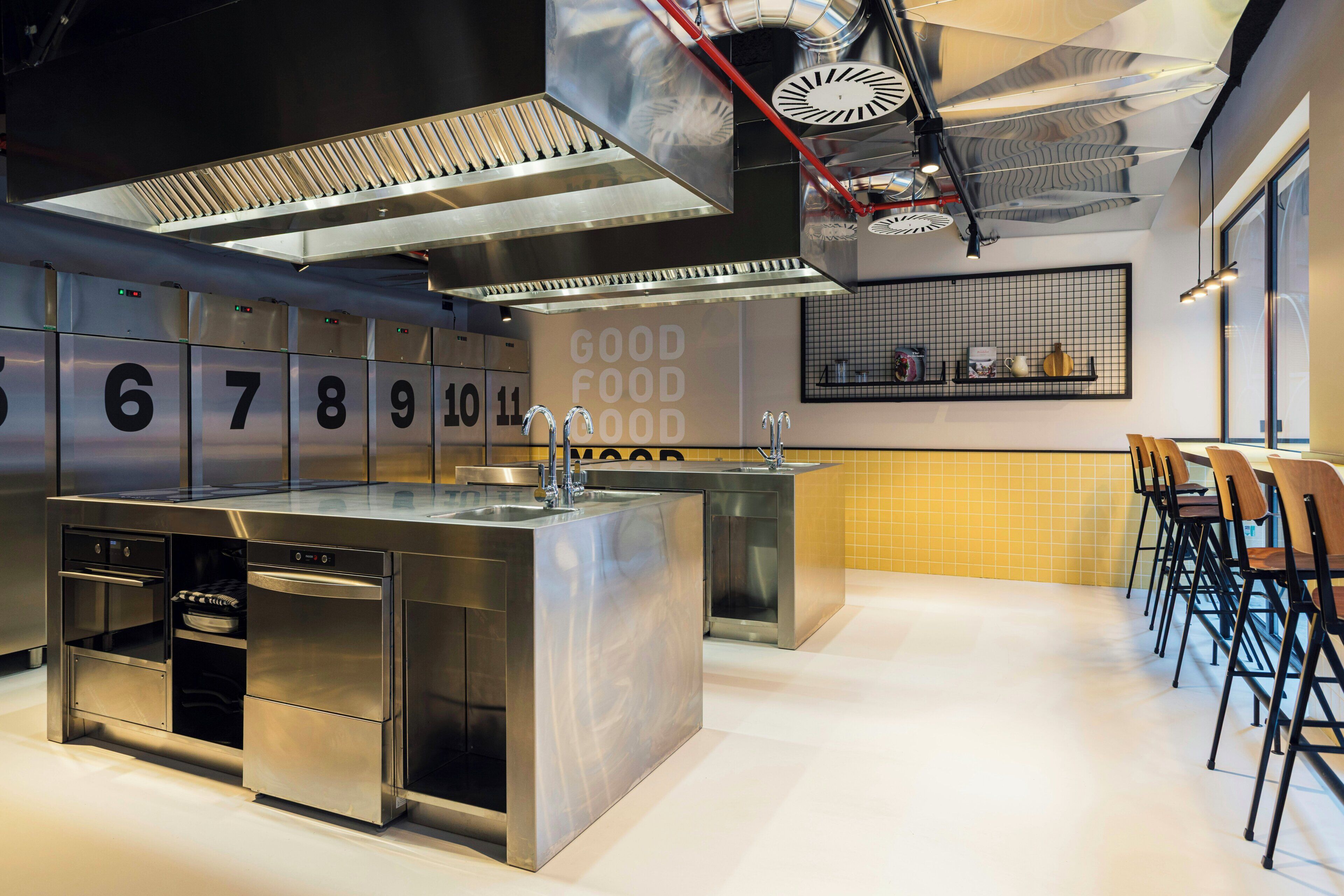 A modern kitchen with stainless steel appliances, a central island, and a seating area with chairs.