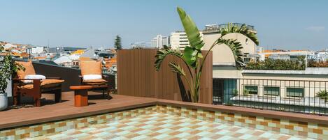 A rooftop pool area with lounge chairs and a tiled floor.