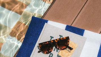 Un libro titulado 'INTER POT' sobre una toalla junto a una piscina.