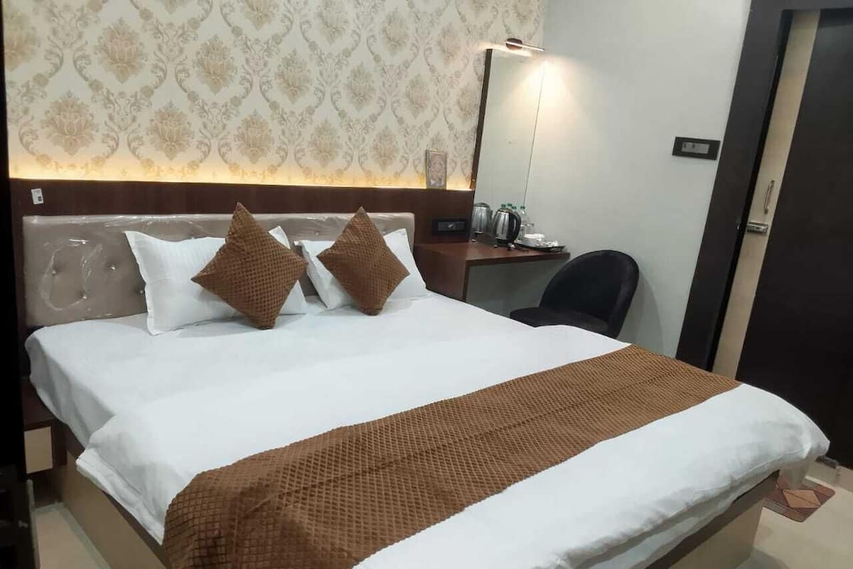 Una cama bien tendida con una colcha blanca y marrón, dos almohadas y una manta marrón.