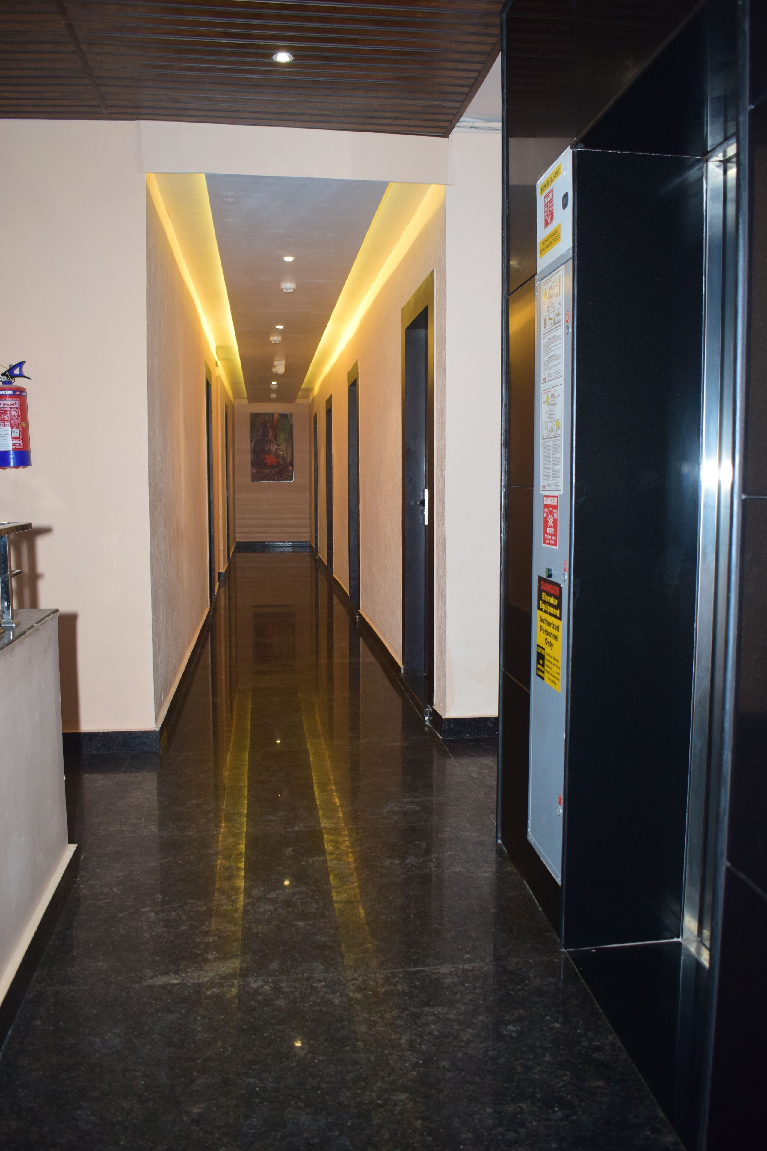 Een hotelgang met een gepolijste vloer, een receptiebalie en een lift.