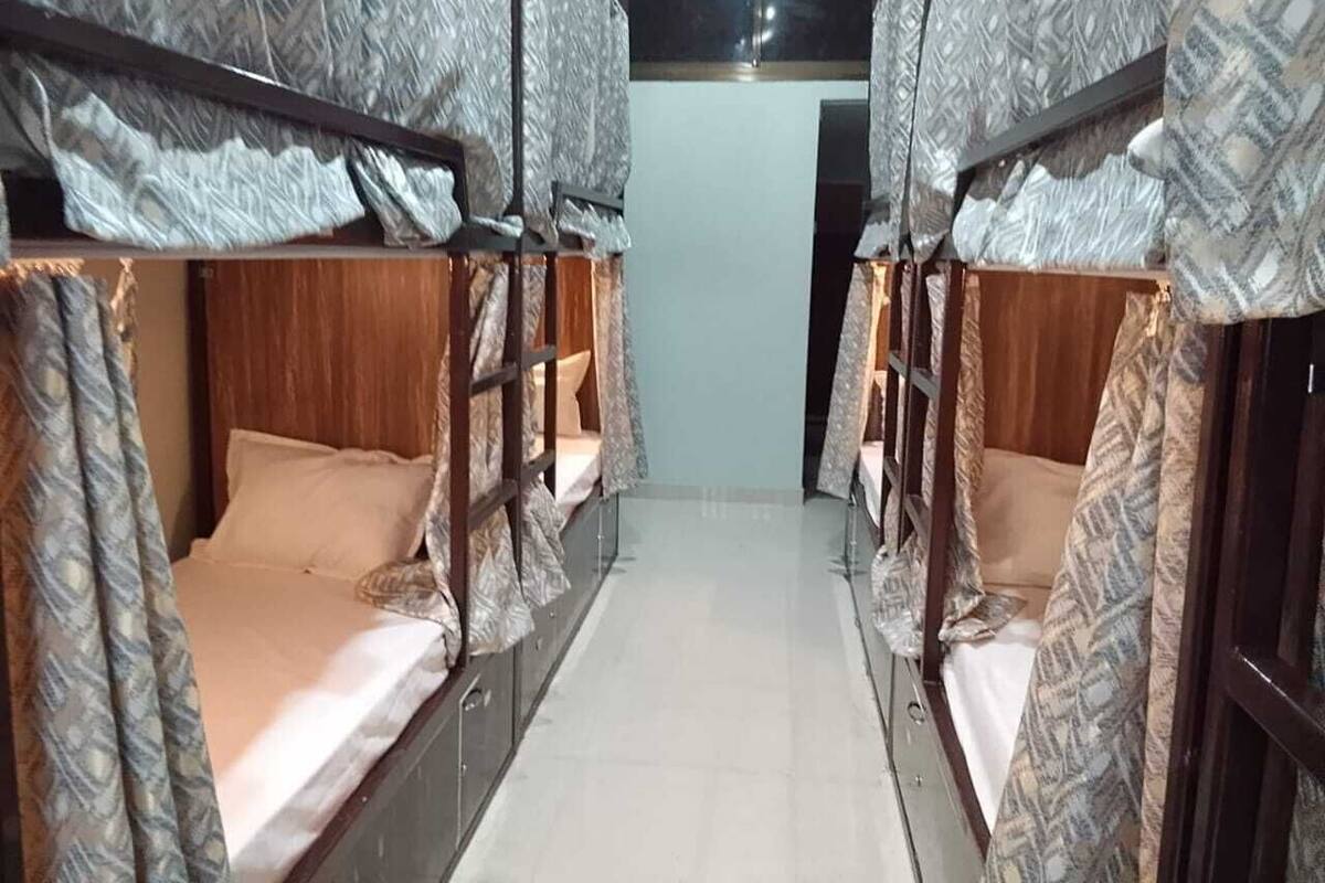 Una habitación con literas dispuestas en fila, cada una con una cortina estampada.