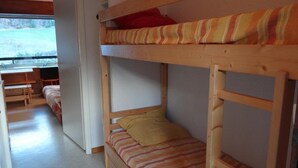 Une chambre avec un lit superposé, une fenêtre, un bureau et une chaise.