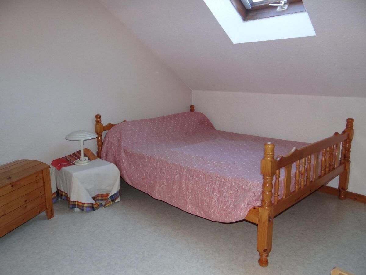 A small, single-bed room with a sloped ceiling and a skylight.