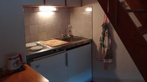 Une cuisine compacte équipée d’un évier, d’une bouilloire et d’un escalier en bois.