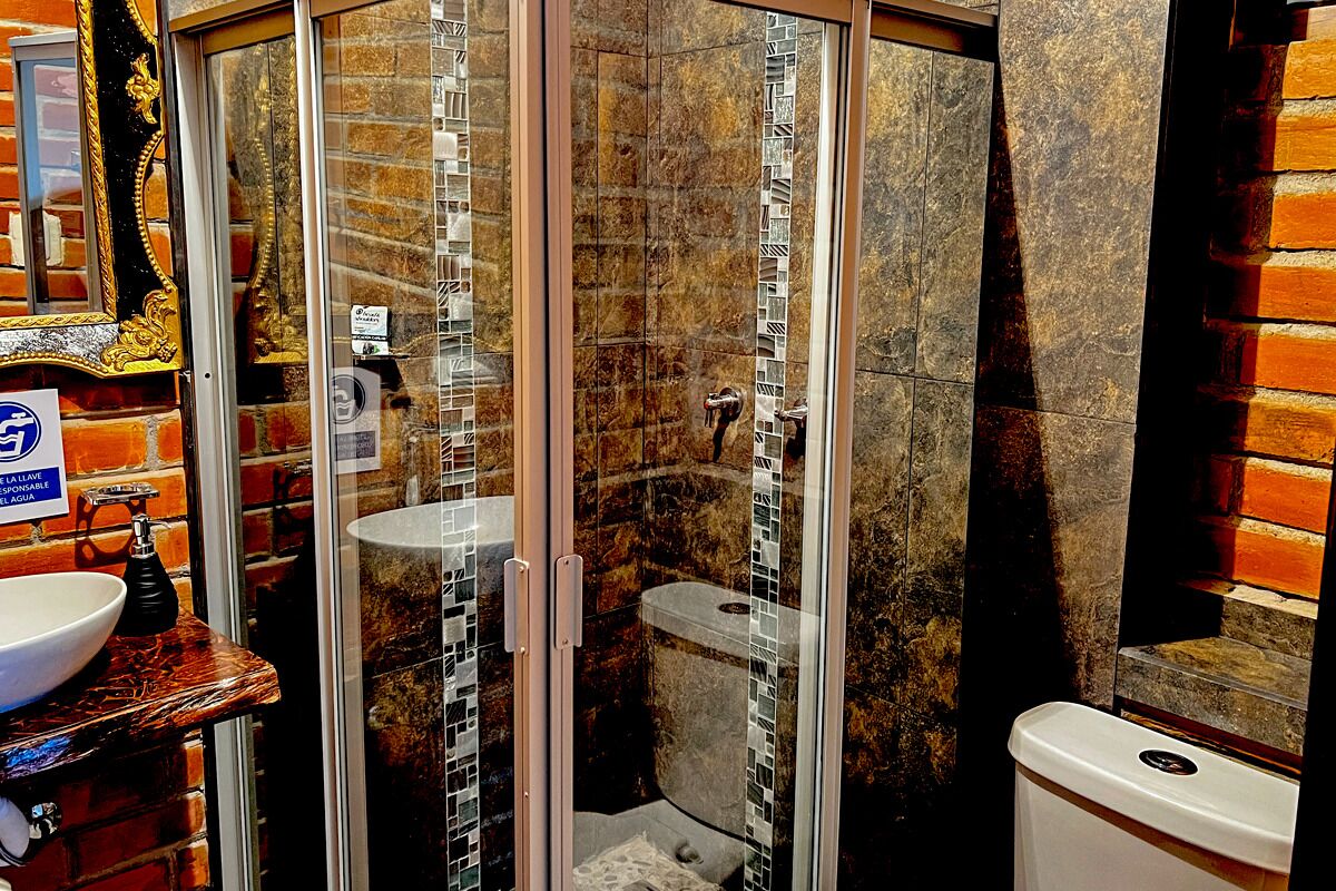 A bathroom with a glass-enclosed shower, a sink with a marble countertop, and a toilet.