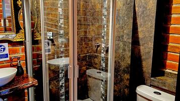 A bathroom with a glass-enclosed shower, a sink with a marble countertop, and a toilet.