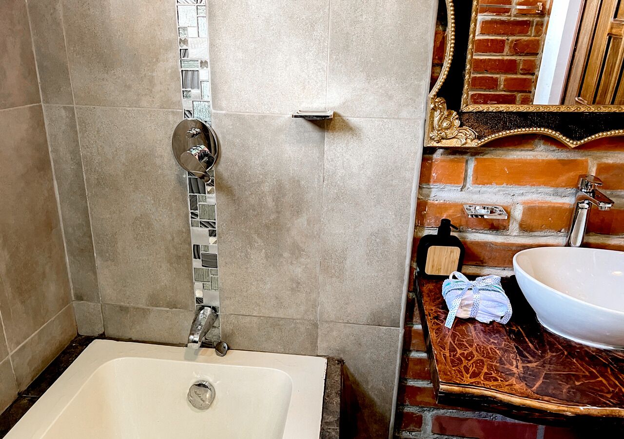 Un bagno con una vasca, un lavandino e uno specchio con cornice decorativa.