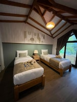 A room with two wooden beds, a wooden ceiling, and a large window.