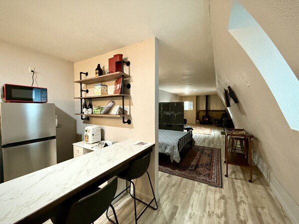 Cocina compacta con refrigerador, microondas y un pequeño comedor.