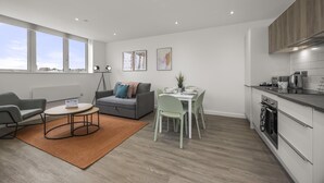 A modern apartment with a dining area, kitchen, and seating space. - Ocean View E By My Getaways (St Leonards-On-Sea)