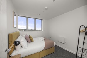 A modern bedroom with a bed, a window, a radiator, and a metal rack. - Ocean View B Free Parking By My Getaways (St Leonards-On-Sea)