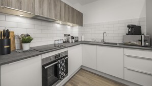 Eine moderne Küche mit weißen Schränken, einer schwarzen Arbeitsplatte und einem eingebauten Backofen.