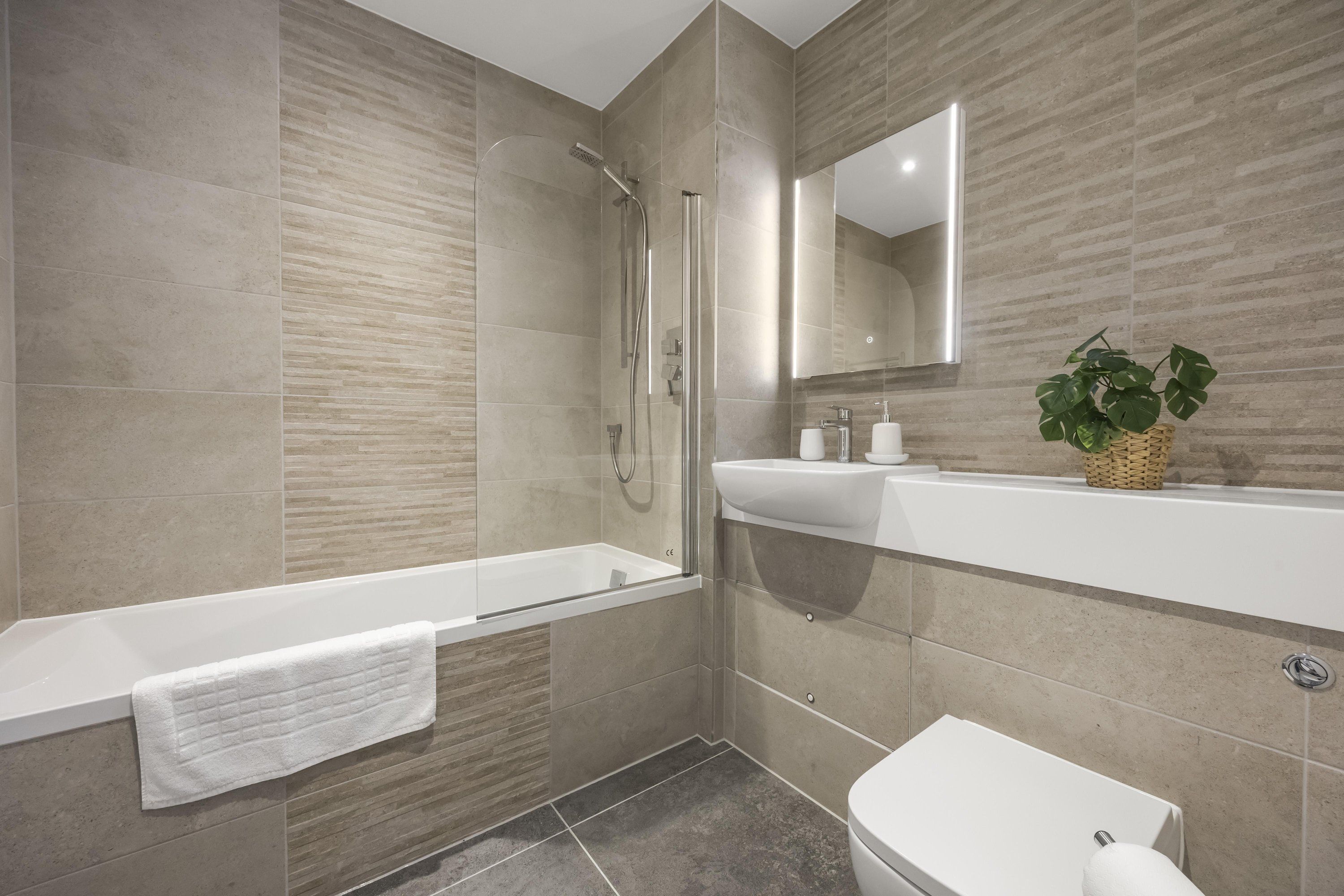 A modern bathroom with a bathtub, shower, and toilet.