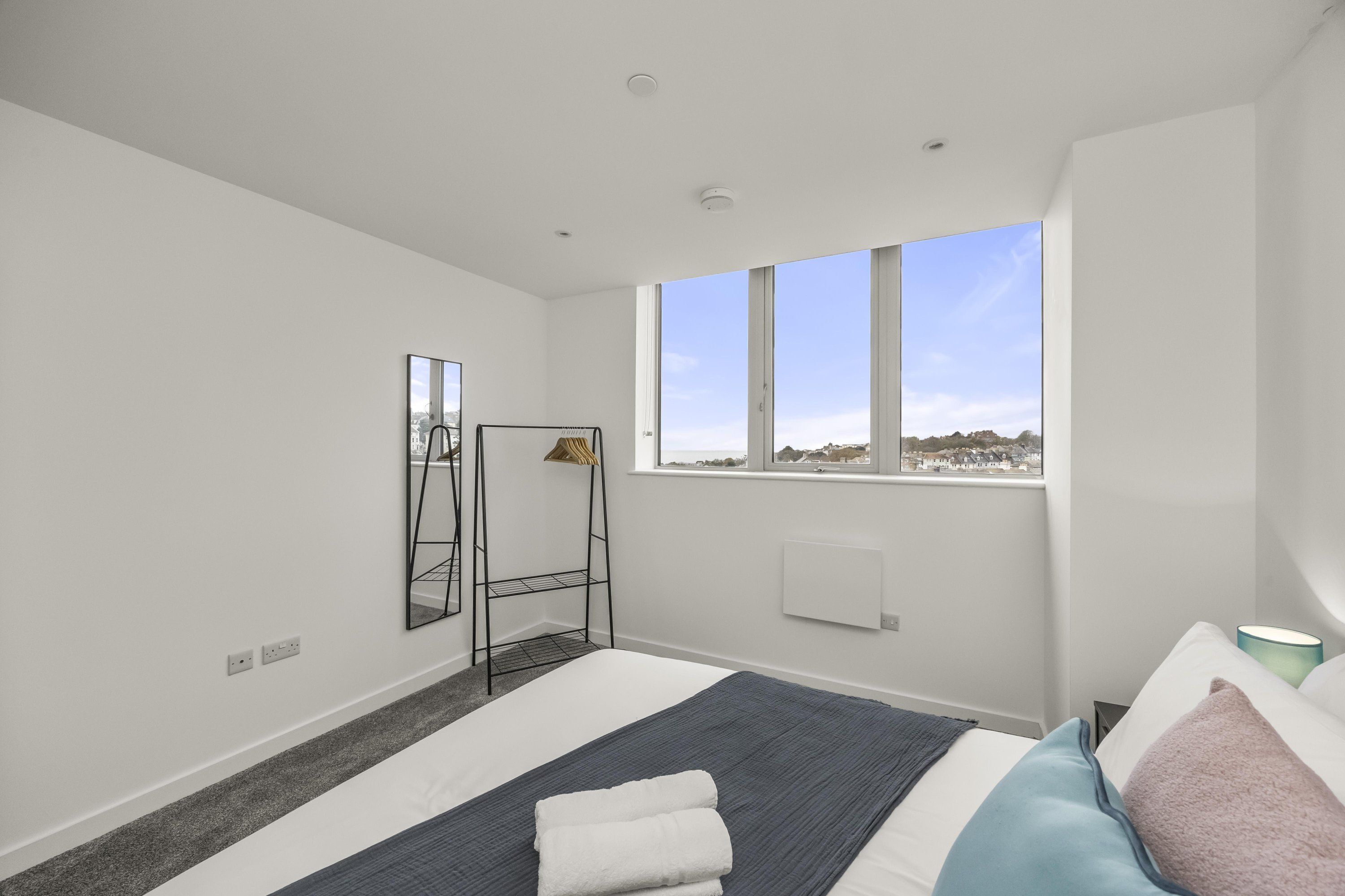 Et moderne hotelværelse med en stor seng, et spejl og et vindue med udsigt over byen.