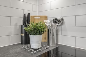A kitchen counter with a potted plant, a cutting board, and kitchen utensils.