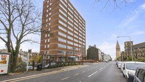 Un immeuble à plusieurs étages, doté d’une architecture moderne, avec une entrée imposante et une enseigne bien visible indiquant la proximité d’une gare.