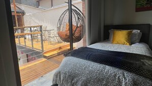 A bedroom with a bed, a hanging chair, and a view of an outdoor patio area.
