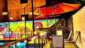 A wooden deck with a pool, outdoor seating, and a colorful mural on the wall.
