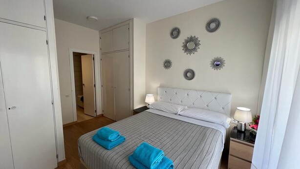 A hotel room with a bed, two bedside tables, a wardrobe, and decorative wall mirrors. - Rooms Paris (Barcelona)