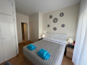 A hotel room with a bed, two bedside tables, a wardrobe, and decorative wall mirrors. - Rooms Paris (Barcelona)