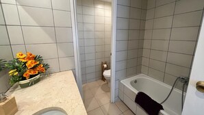 A bathroom with a bathtub, toilet, and sink. - Rooms Paris (Barcelona)