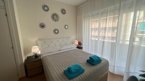 A neatly arranged bedroom with a bed, bedside tables, and decorative wall art. - Rooms Paris (Barcelona)