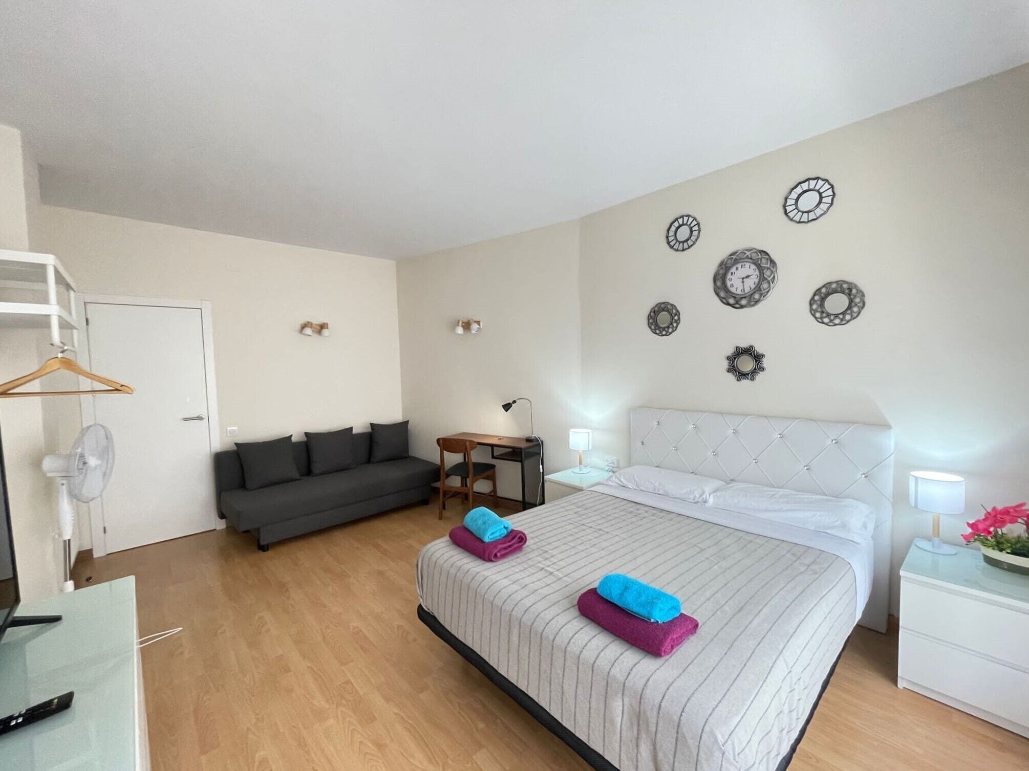 A modern hotel room with a bed, a sofa, a desk, and a chair.