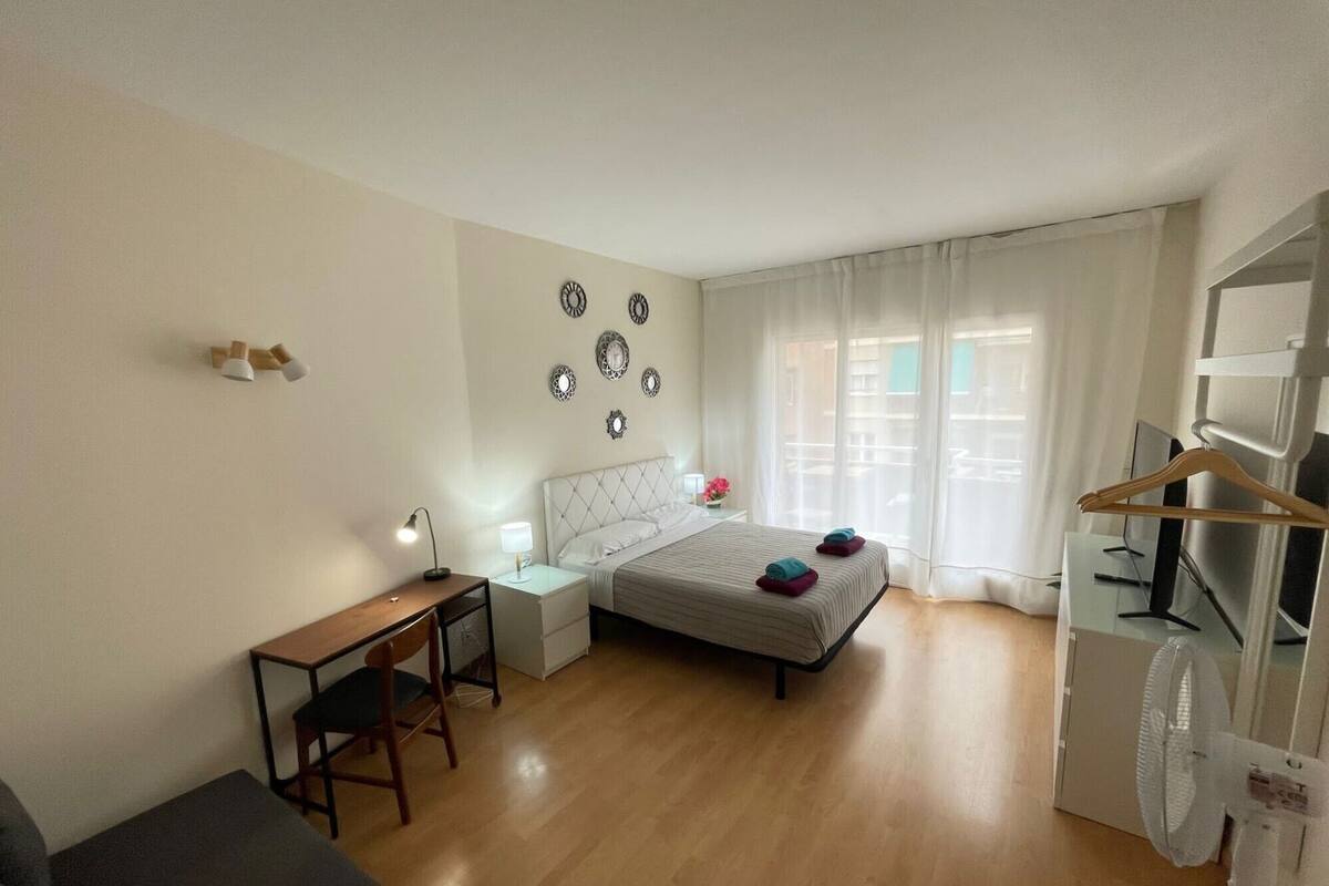 A compact hotel room with a bed, a desk, a chair, a TV, and a wardrobe.